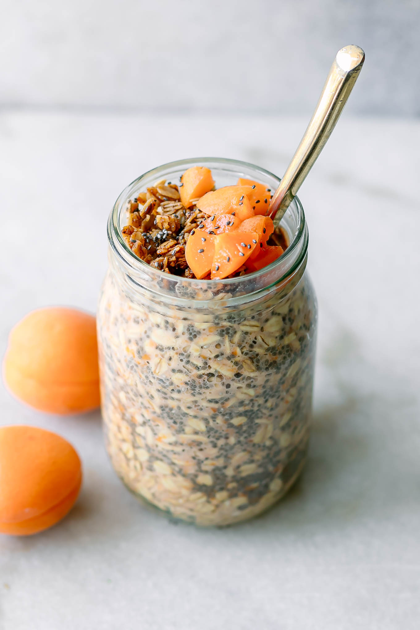a jar of apricot overnight oats with a gold fork on a white table