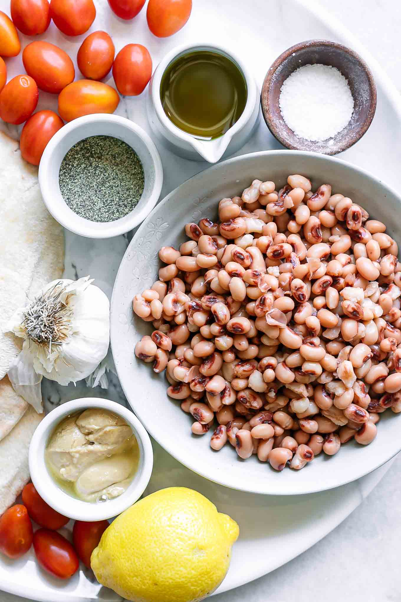bowls with black eyed peas, tahini, oil, garlic, lemon, salt, and pepper for hummus