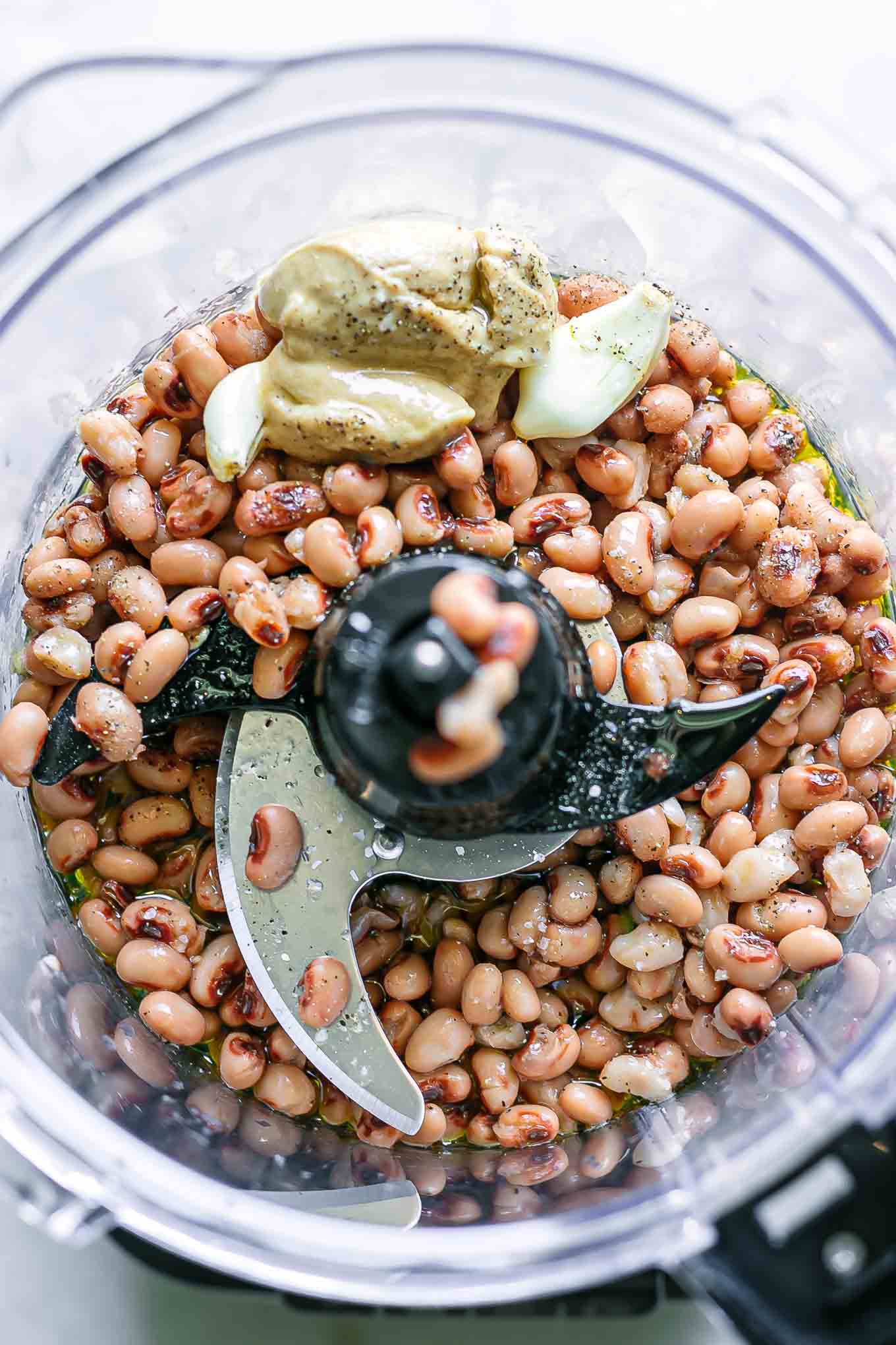 black eyed peas, tahini, salt, oil, pepper, and garlic in a food processor before blending for hummus
