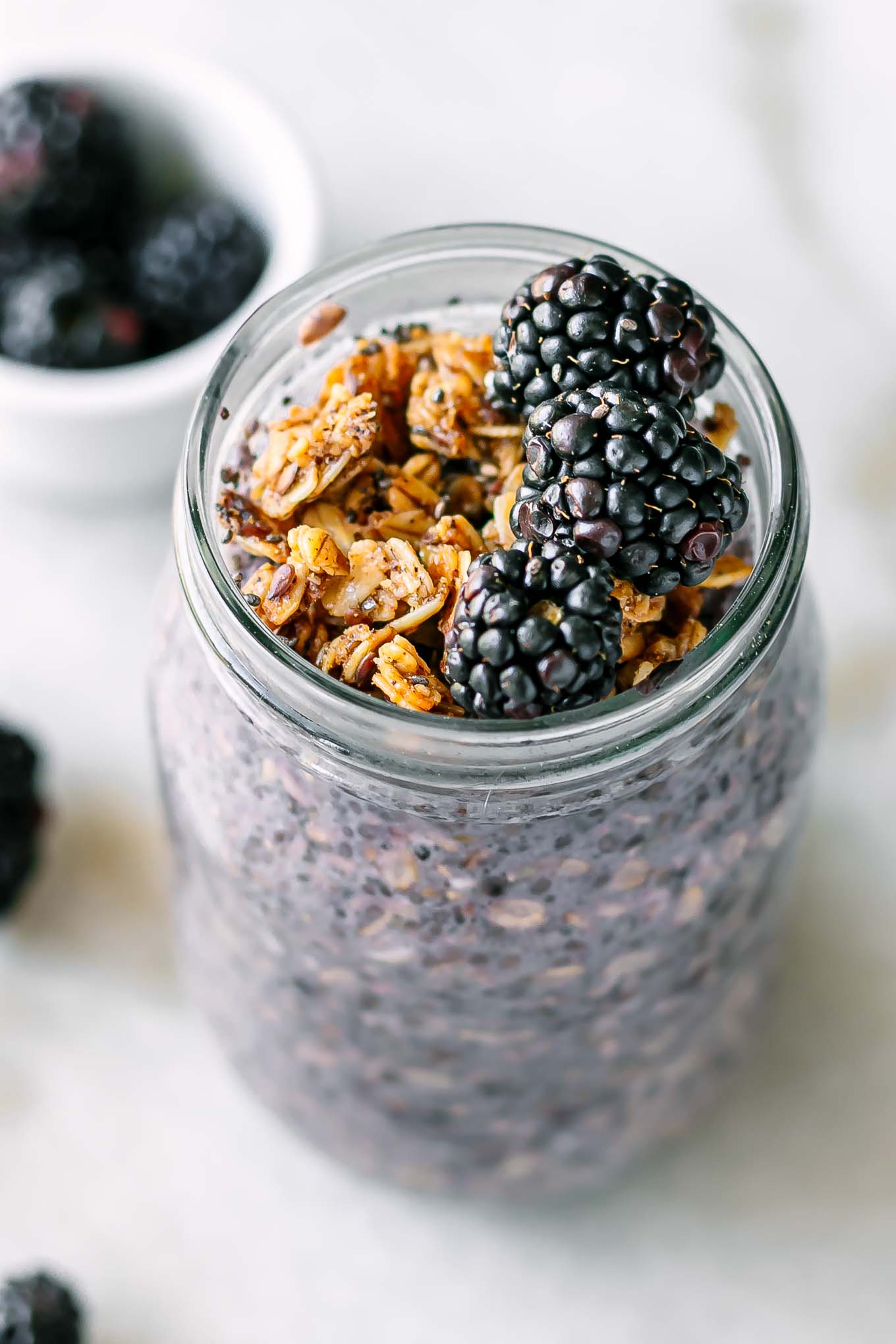 a jar of blackberry chia pudding garnished with blackberries and granola