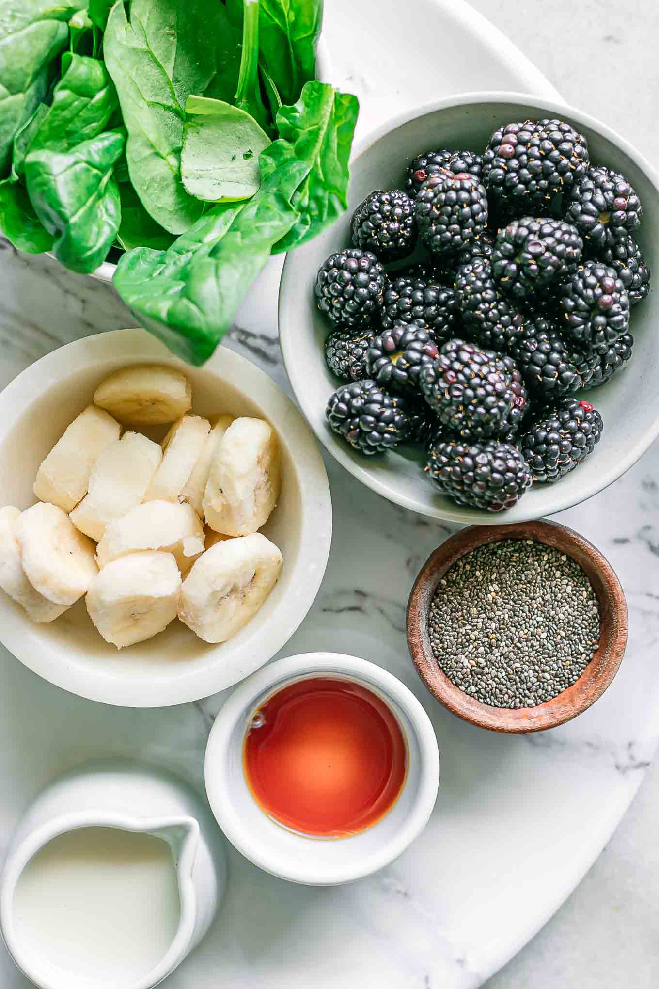 bowls of blackberries, spinach, bananas, chia seeds, vanilla, and milk for a smoothie