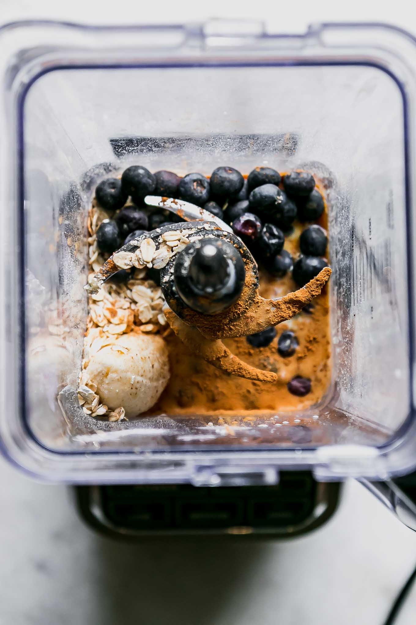a blender with blueberries, oats, banana, cinnamon, and vanilla for a smoothie