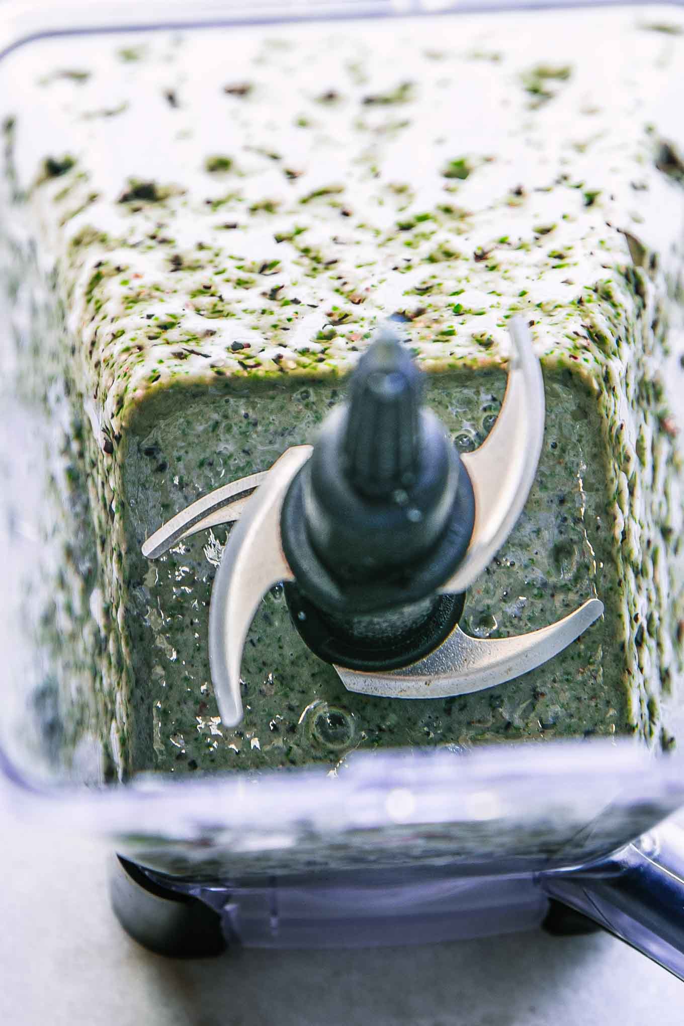 a blended smoothie with blueberries and spinach inside a blender