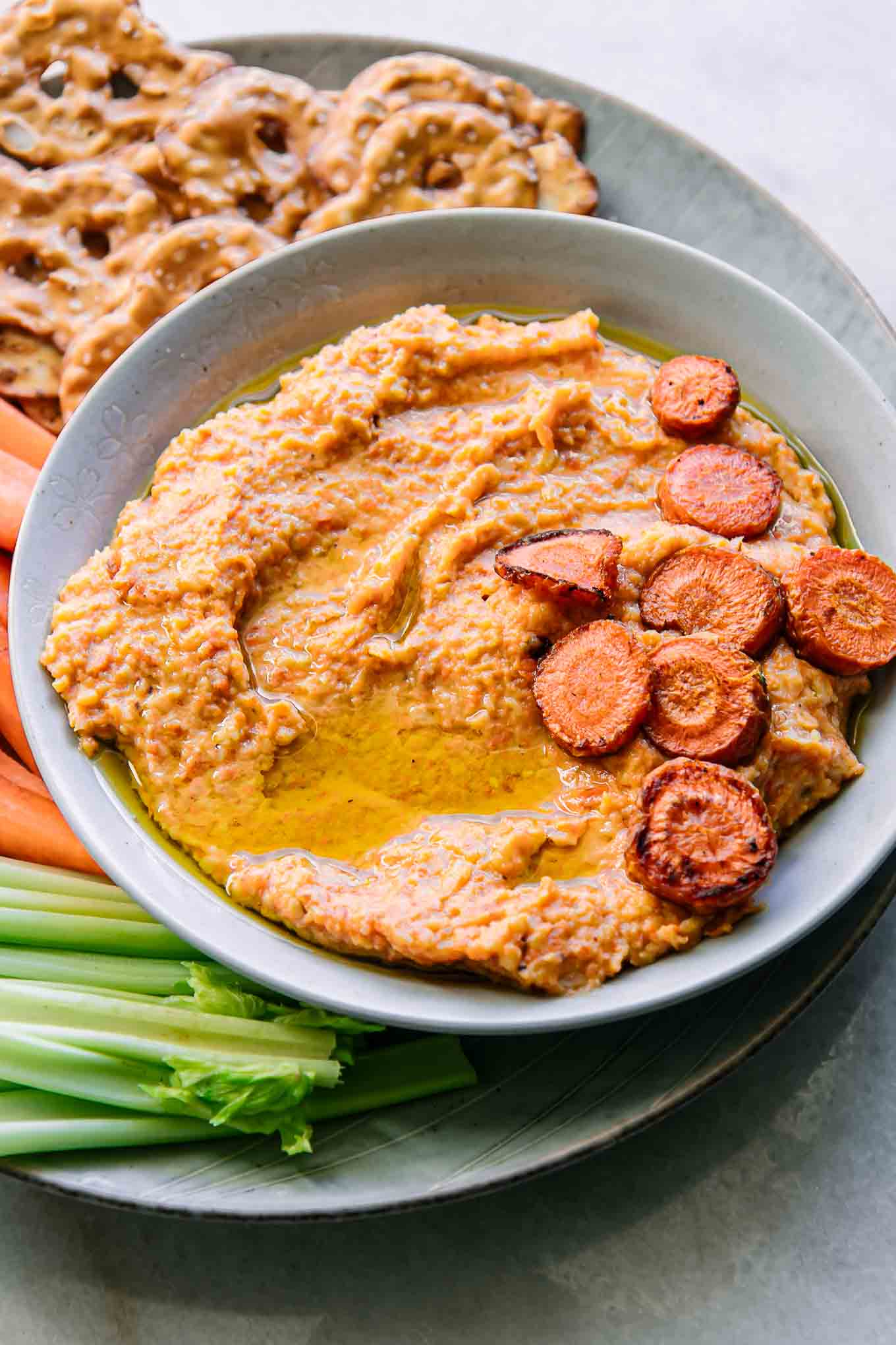a bowl of roasted carrot hummus dip on a white table