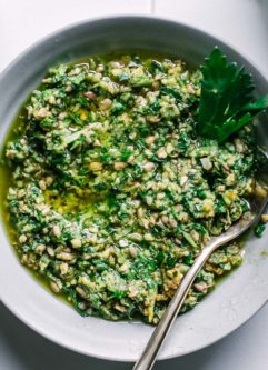 celery greens pesto in a small white bowl on a white table