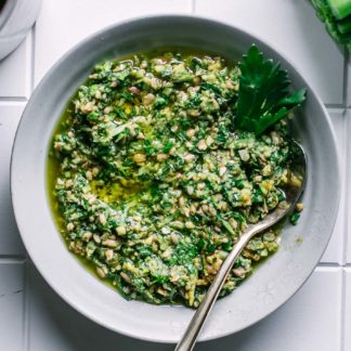 celery greens pesto in a small white bowl on a white table