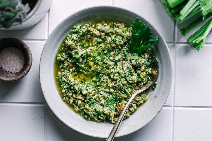 celery greens pesto in a small white bowl on a white table