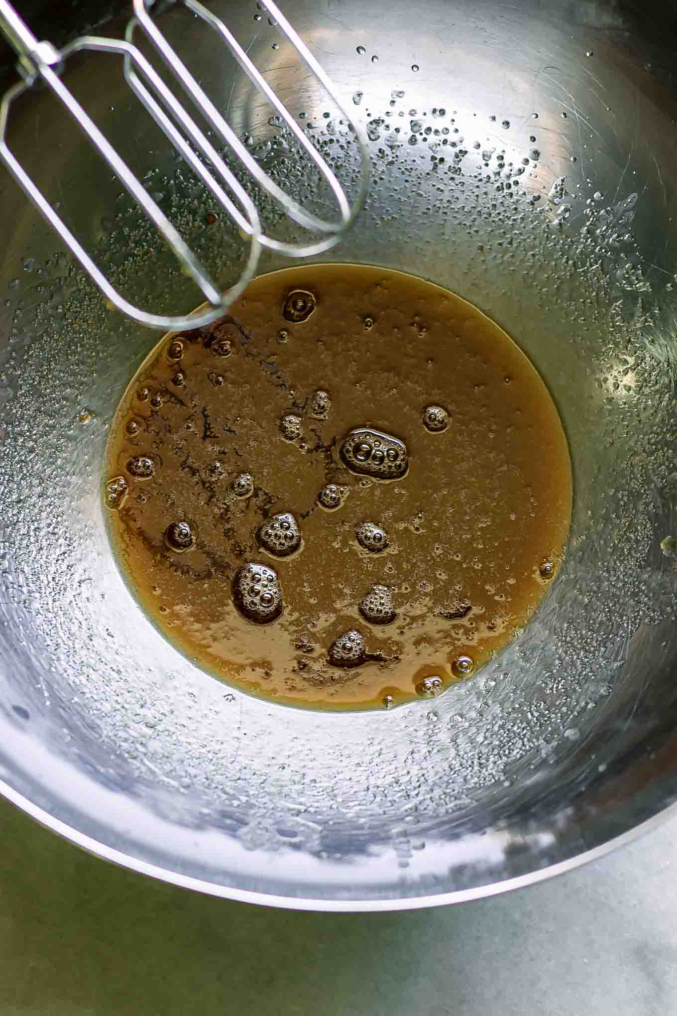 a metal mixing bowl with vegan butter mixed with brown sugar and vanilla extract