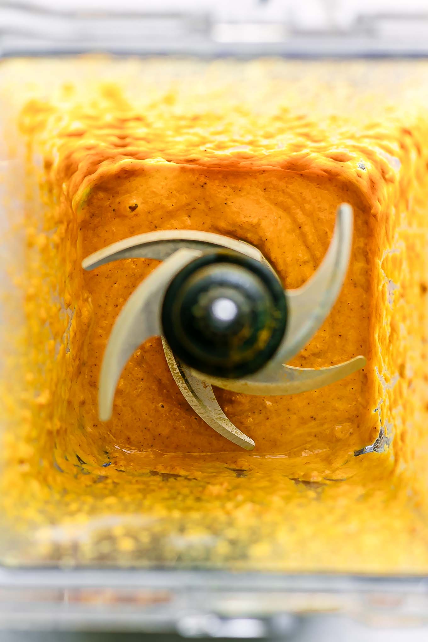 a blender with yellow tahini curry sauce