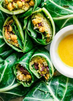 collard greens wraps with chickpea quinoa tahini curry salad on a white plate on a white table