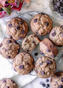 vegan banana bread muffins with chocolate ships on a cooling rack on a white table