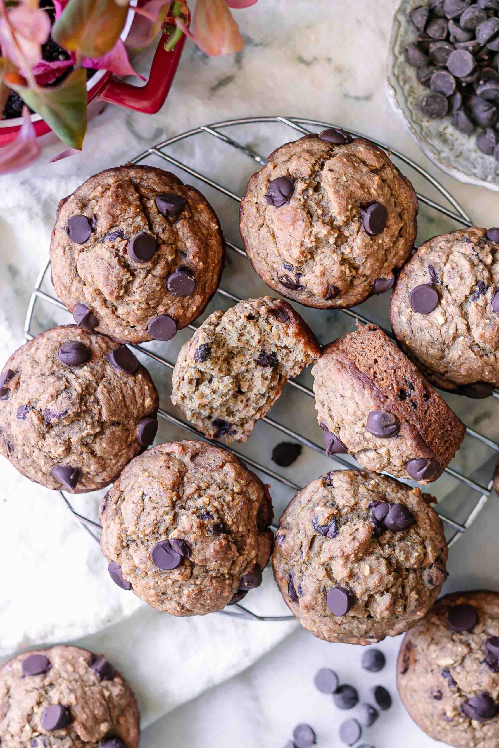vegan banana bread muffins with chocolate ships on a cooling rack on a white table