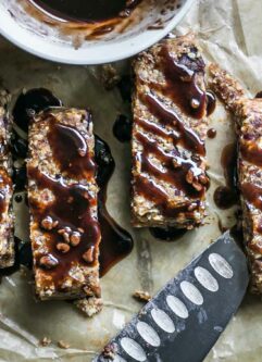 homemade peanut butter granola bars with chocolate drizzled on top on parchment paper