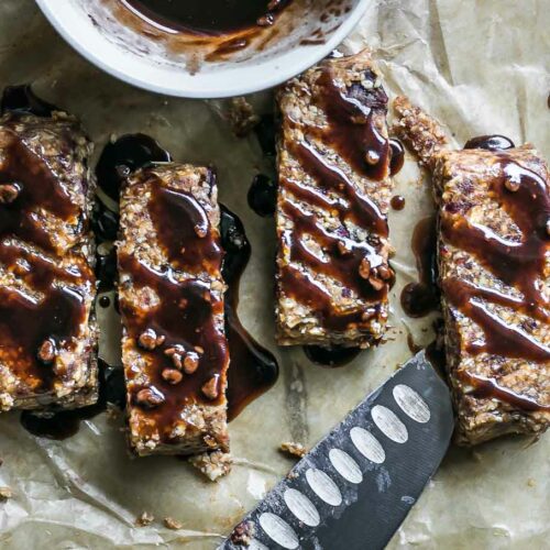 homemade peanut butter granola bars with chocolate drizzled on top on parchment paper