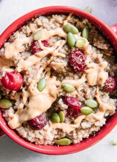 a red bowl of cranberry oatmeal with a gold fork on a white table