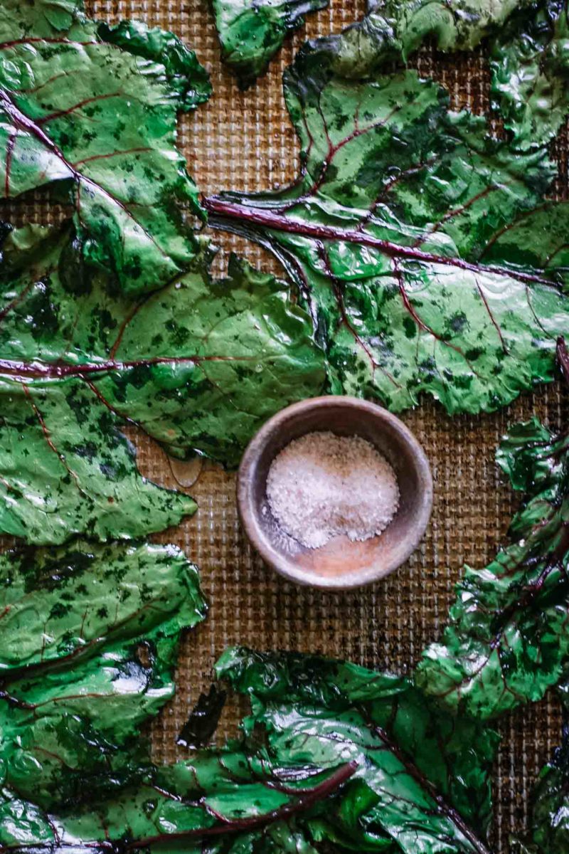 baked beet leaves on a sheet pan with a bowl of salt