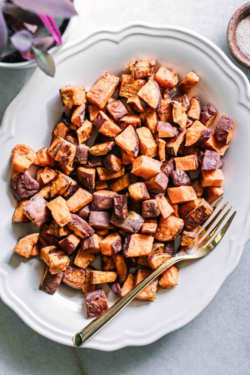 crispy baked sweet potatoes on a white plate with gold fork