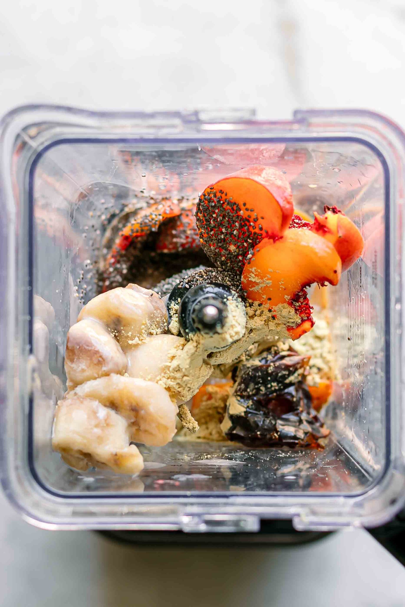 peaches, bananas, and other smoothie ingredients inside a blender
