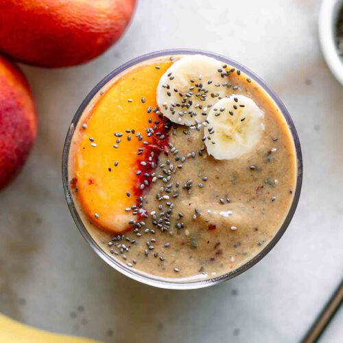 the top of a smoothie with peach and banana slices on a white table