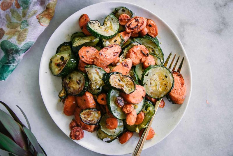 baked carrots and zucchini with garlic on a white plate