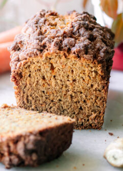 a sliced loaf of carrot cake bread on a table with fresh ginger and carrot