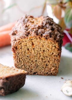 a loaf of carrot cake bread on a white table with cut slices