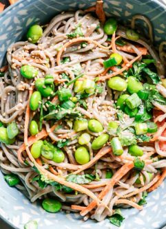 a blue bowl with sesame ginger soba noodle salad on a white table