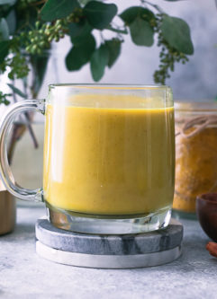 a yellow golden milk latte in a glass mug with cinnamon sticks