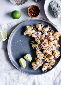 A blue plate with oven roasted cauliflower topped with gorgonzola and lime.