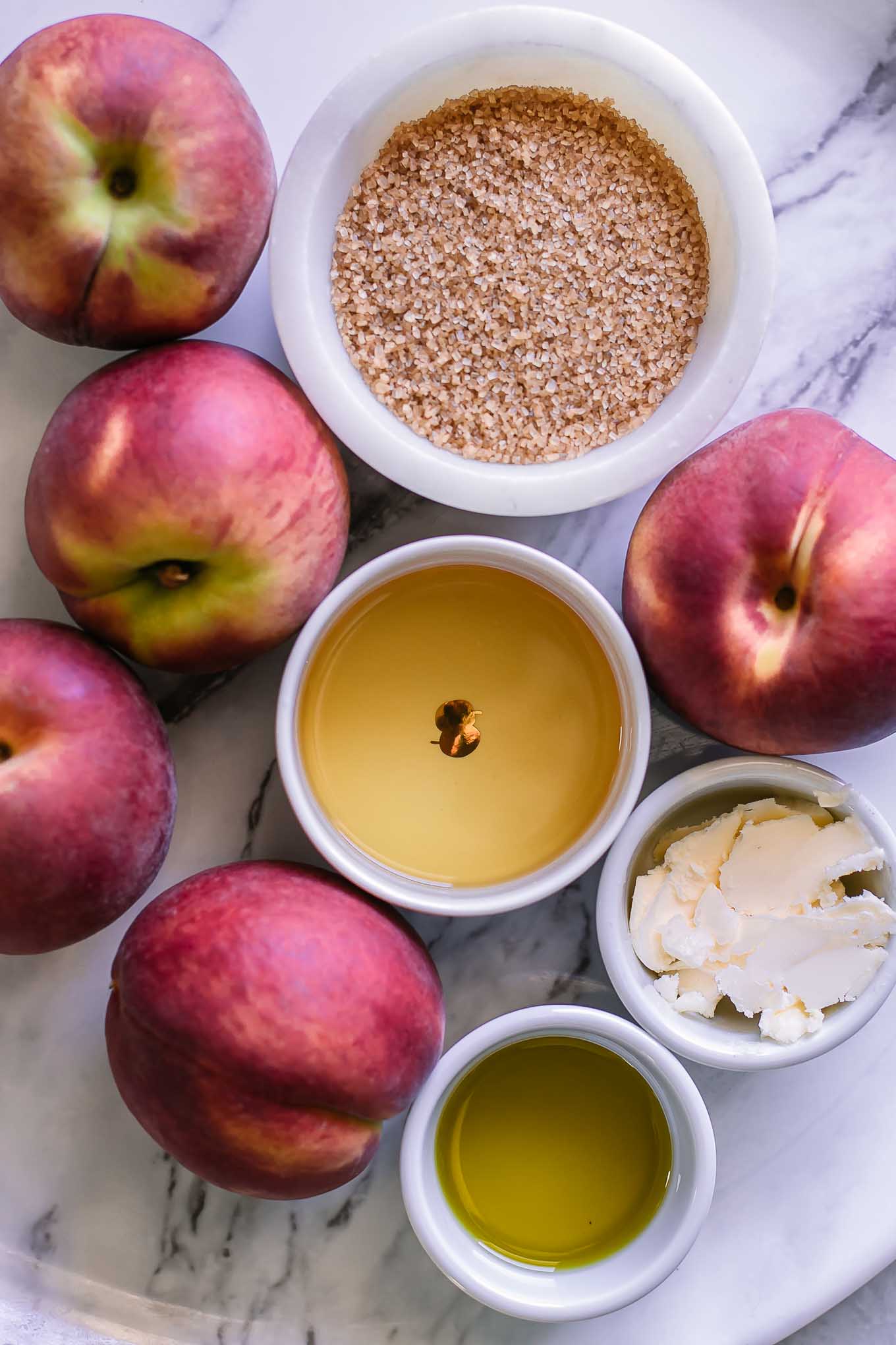 peaches, bourbon, brown sugar, butter, and oil on a white table