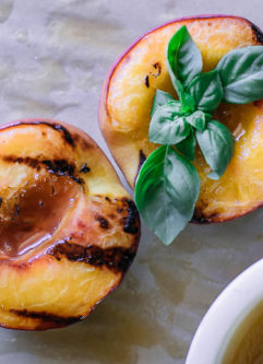 grilled peach halves on a table with drizzled sauce