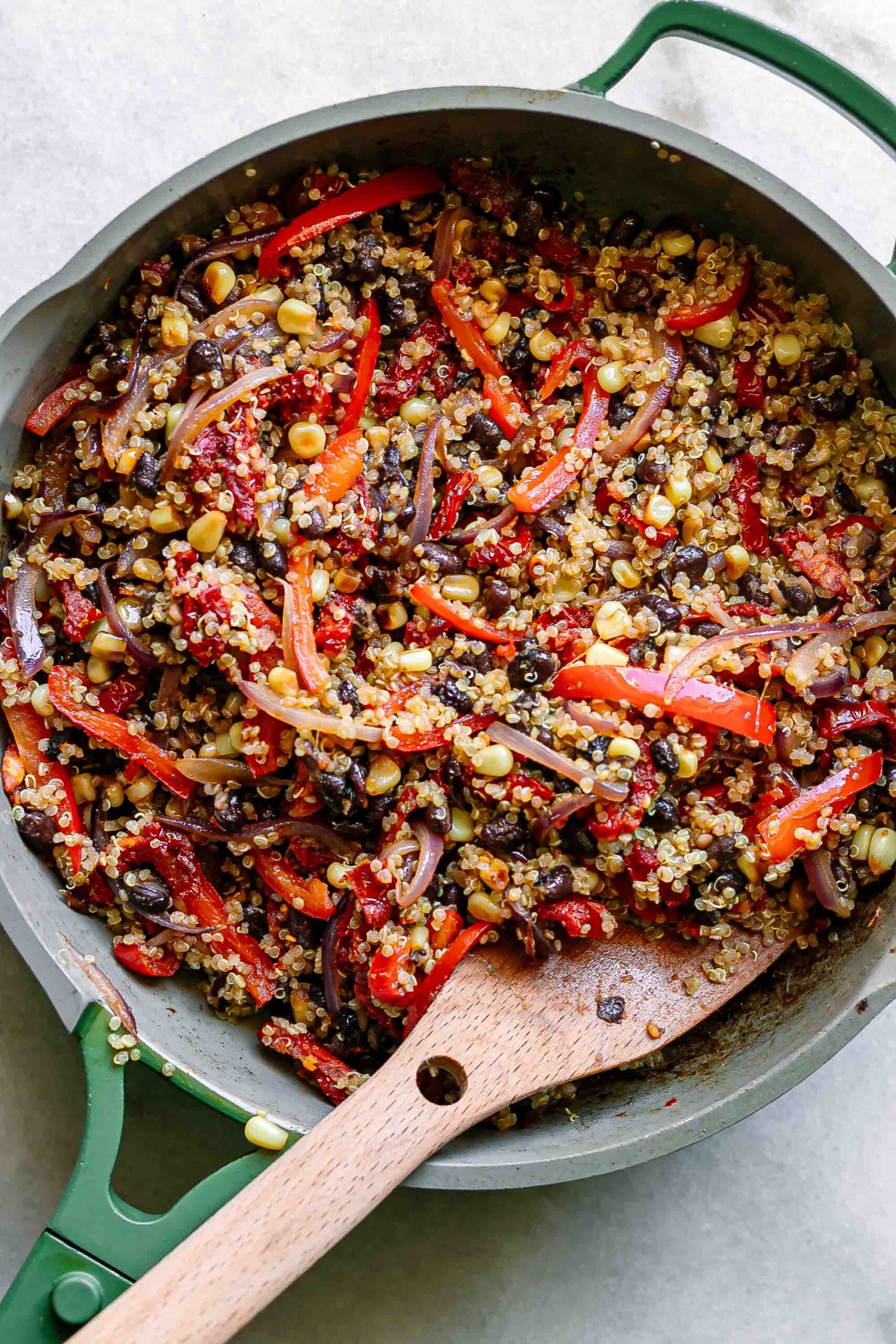 quinoa, black beans, and vegetables in a pan with a wooden spoon