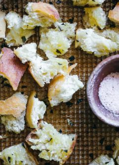 baked ciabatta croutons on a baking sheet with a bowl of salt
