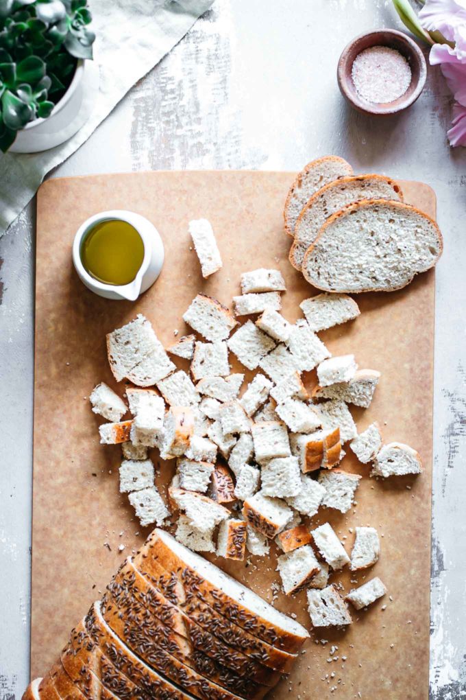 sliced rye bread on cutting board with bowls of oil and salt
