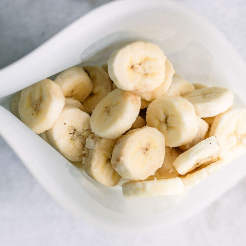 a freezer bag with frozen banana slices on a white table