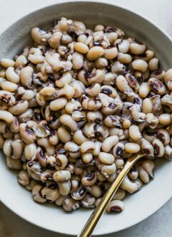 a white bowl with cooked black eyed peas on a white table