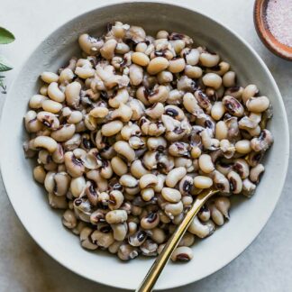 a white bowl with cooked black eyed peas on a white table