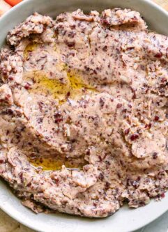a bowl of kidney bean hummus on a plate with pita bread for dipping
