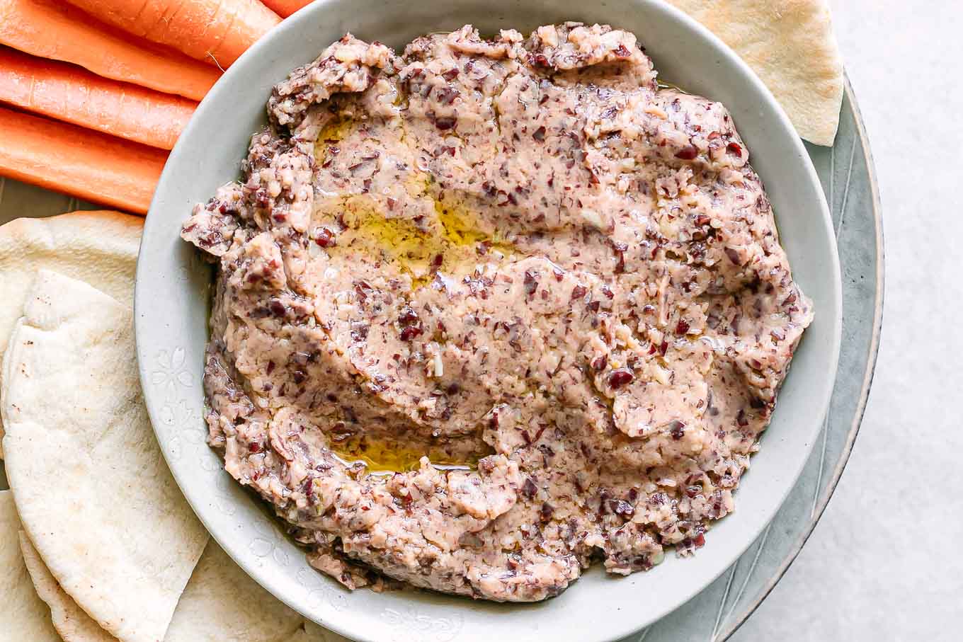 a bowl of kidney bean hummus on a plate with pita bread for dipping