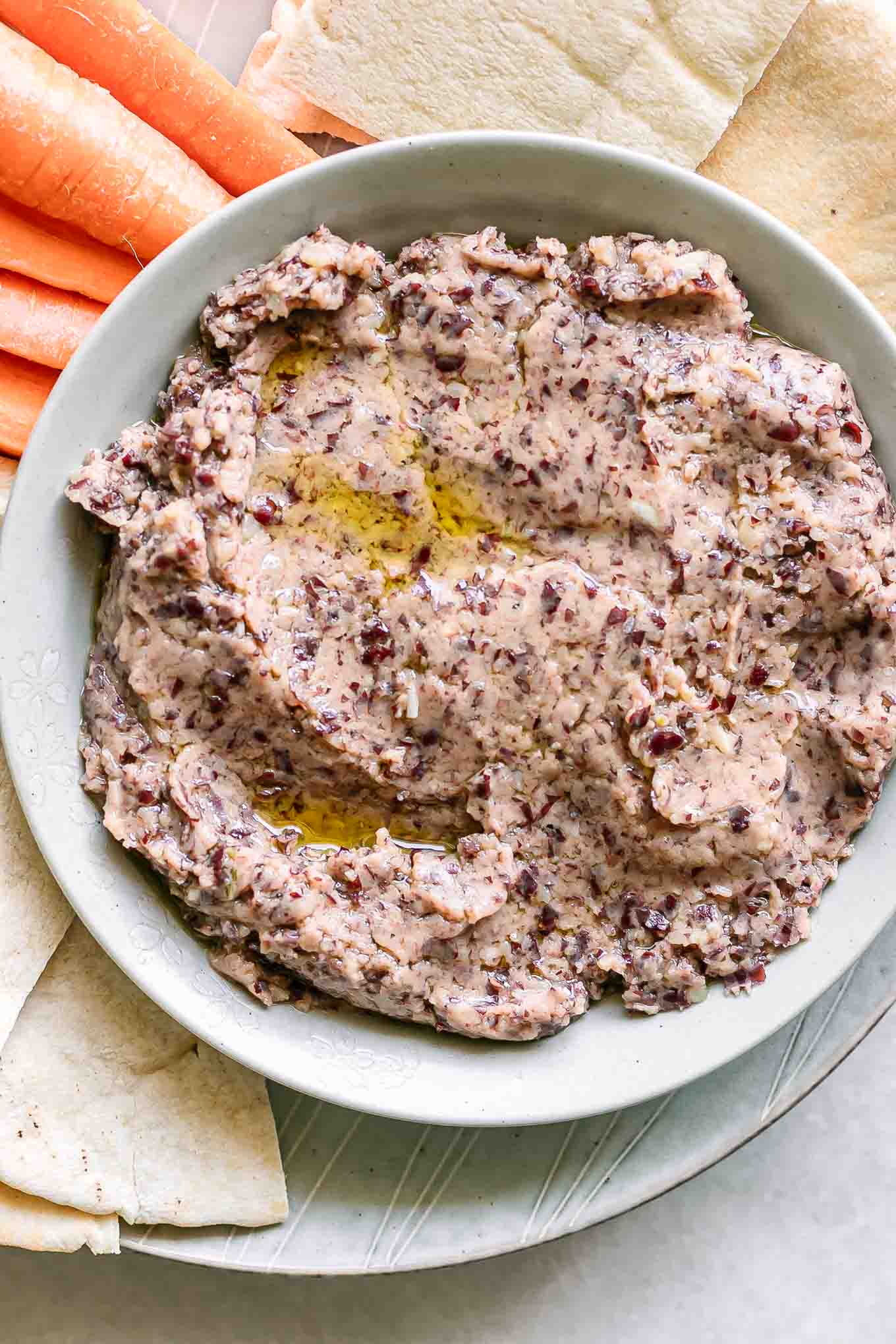 a bowl of hummus made with kidney bean hummus on a plate with vegetables for dipping