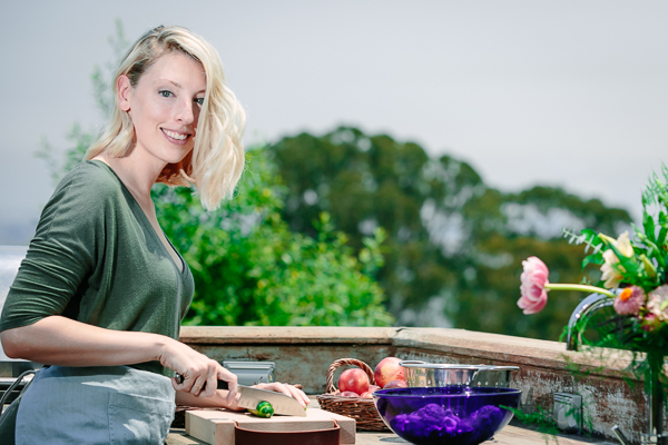 Kristina Todini, RDN of Fork in the Road cutting vegetables in an outdoor kitchen.