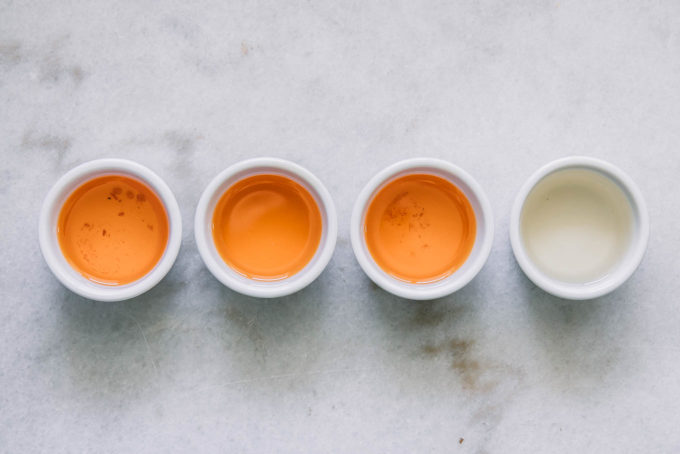 three small ramekins of sun-dried tomato oil and one small ramekin of white wine vinegar on a white countertop