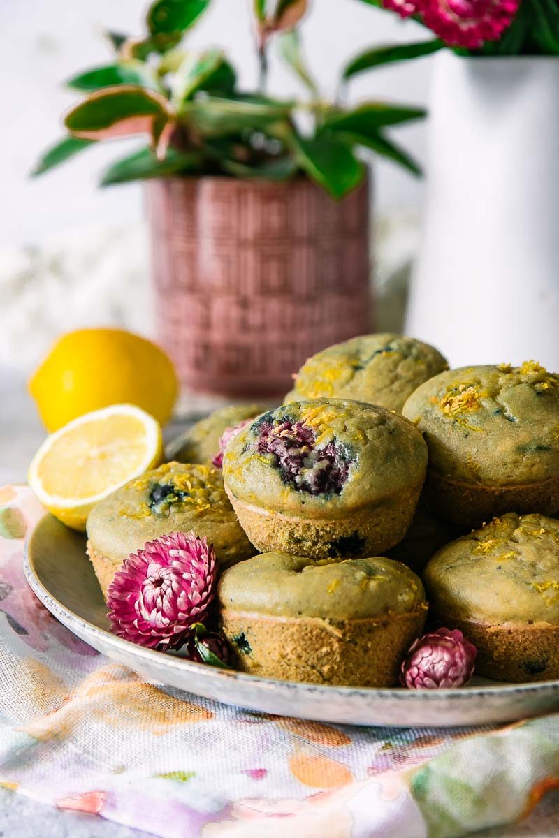 a plate with stacked lemon berry muffins and flowers on a white table