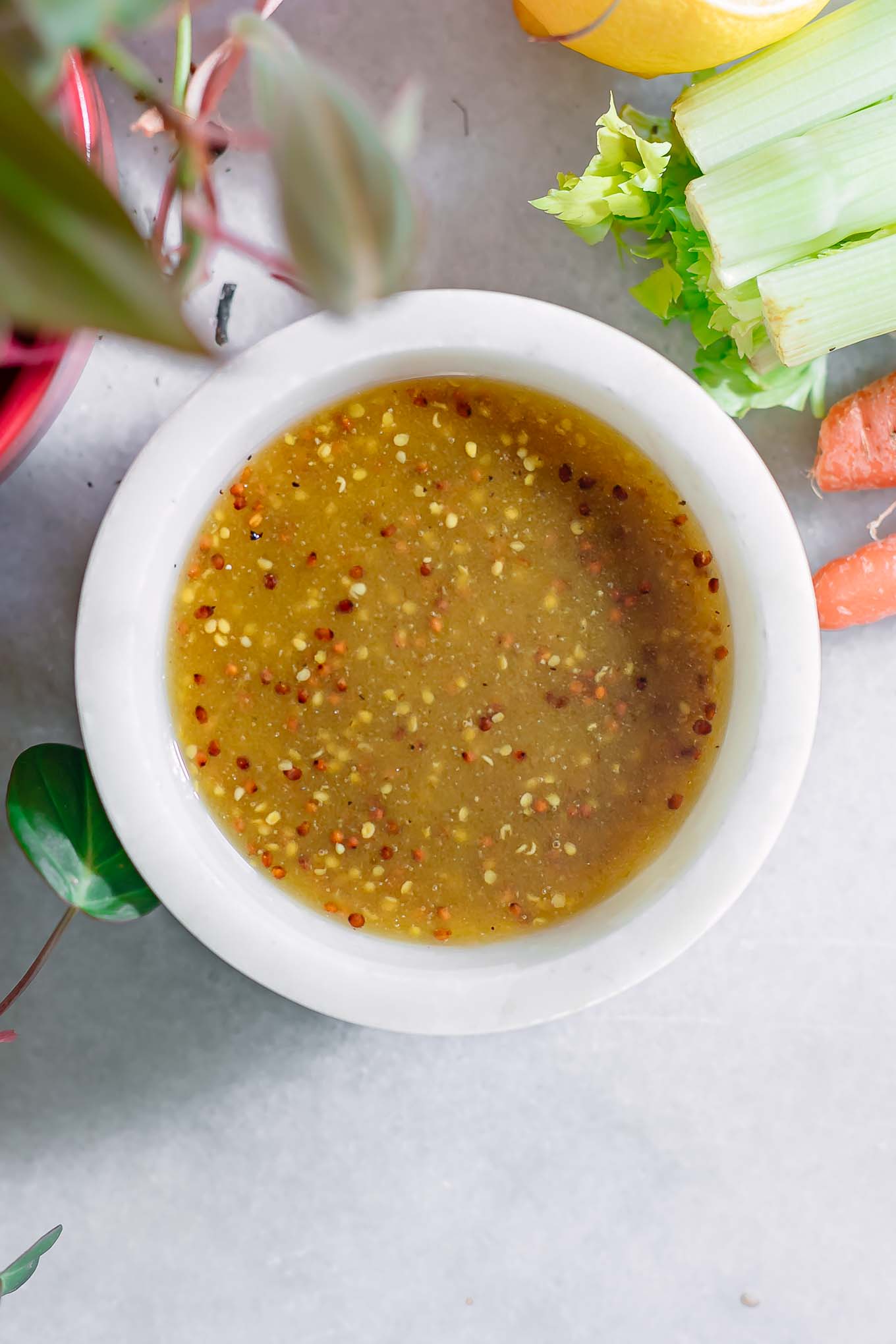 a white bowl with dijon and maple syrup salad dressing on a white table