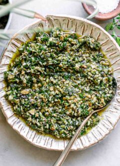 oregano pesto sauce on a white plate with a gold fork