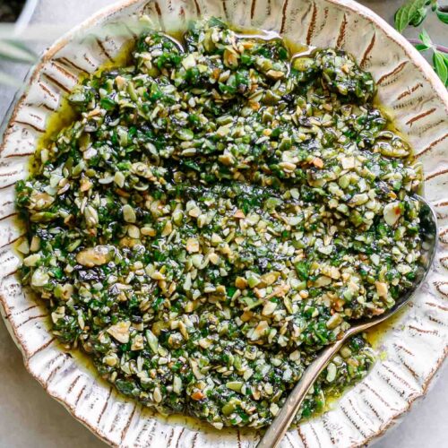 oregano pesto sauce on a white plate with a gold fork