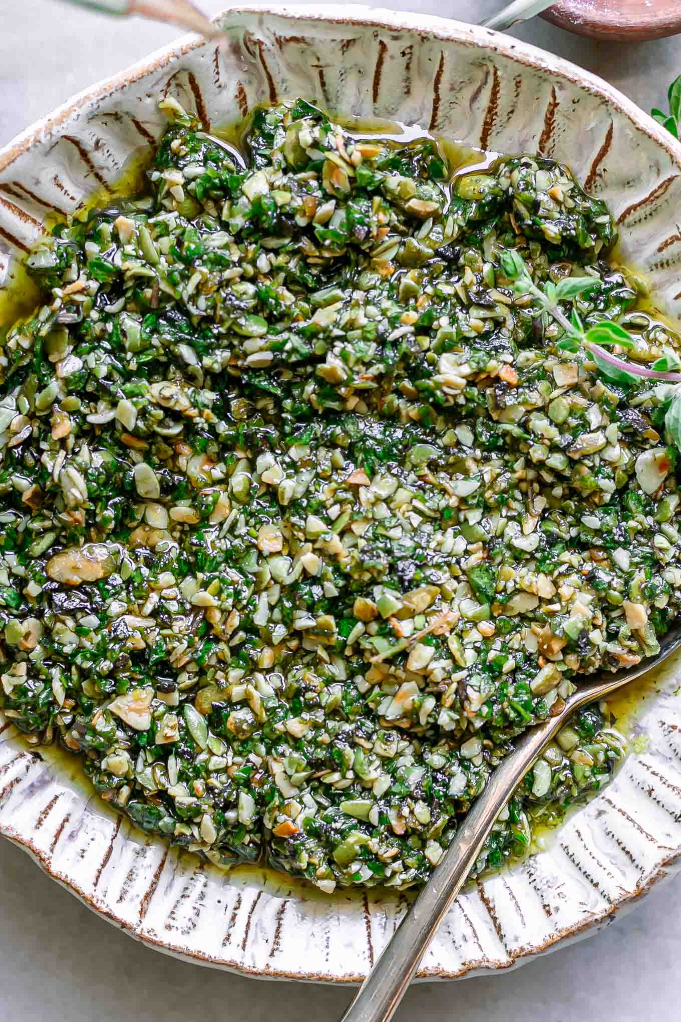 a close up photo of oregano pesto sauce in a white bowl