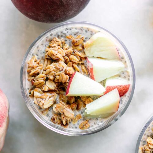 a bowl of peach chia seed pudding with granola and sliced peaches as garnish