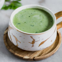 a mug of matcha green tea latte with a mint leaf and a sprinkle of green tea powder on top