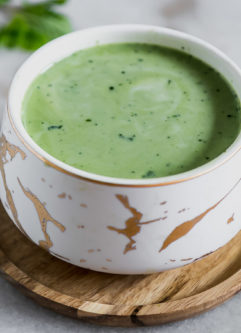 a mug of matcha green tea latte with a mint leaf and a sprinkle of green tea powder on top